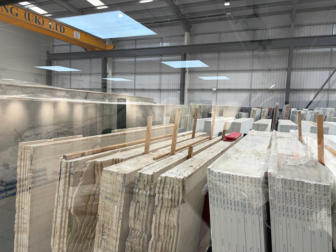 Bundles of Calacatta Venatino quartz and natural travertine slabs in stock